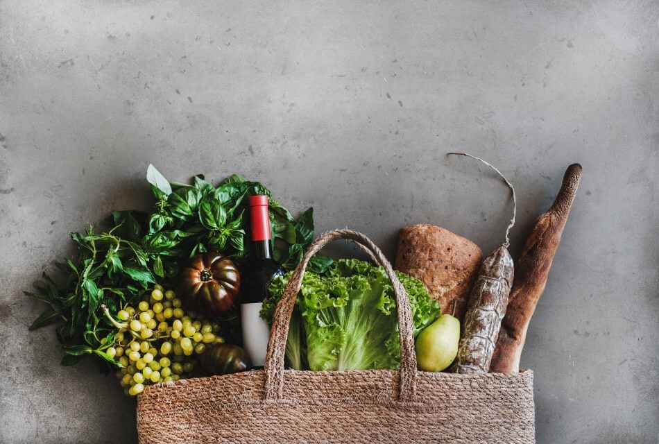 A burlap bag with handles full of fresh vegetables.