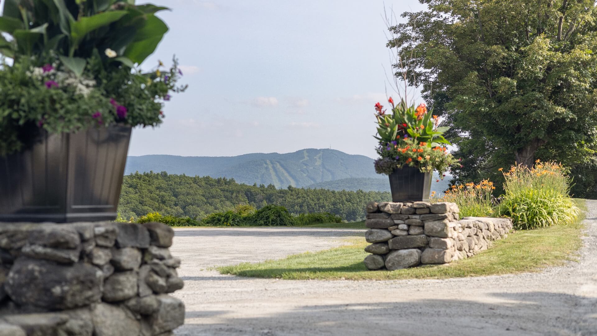 Two stone walls with flower pots on them, and sweeping mountains in the background.